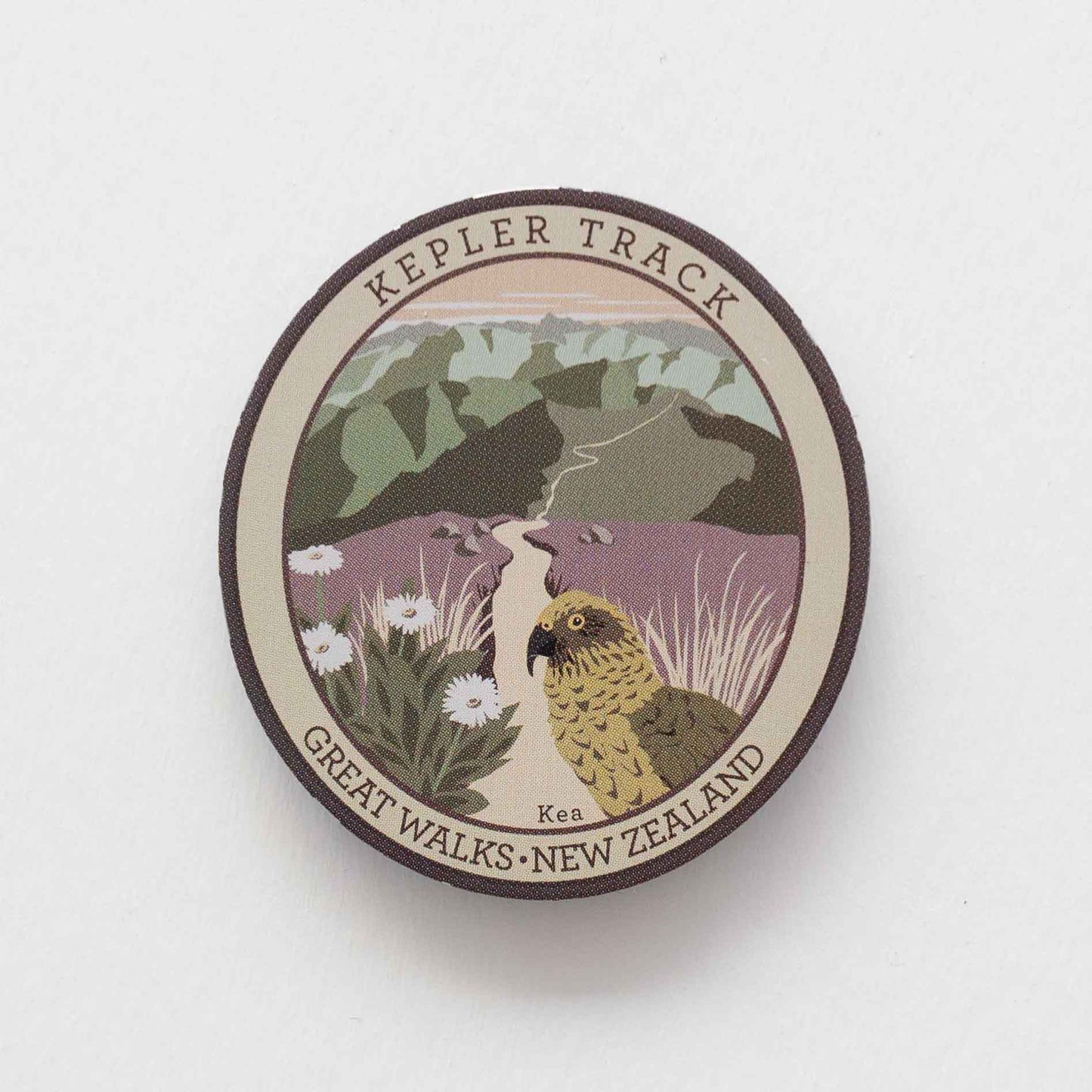 Oval Kepler Track pin, with a kea, mountain daisy and alpine ridges.