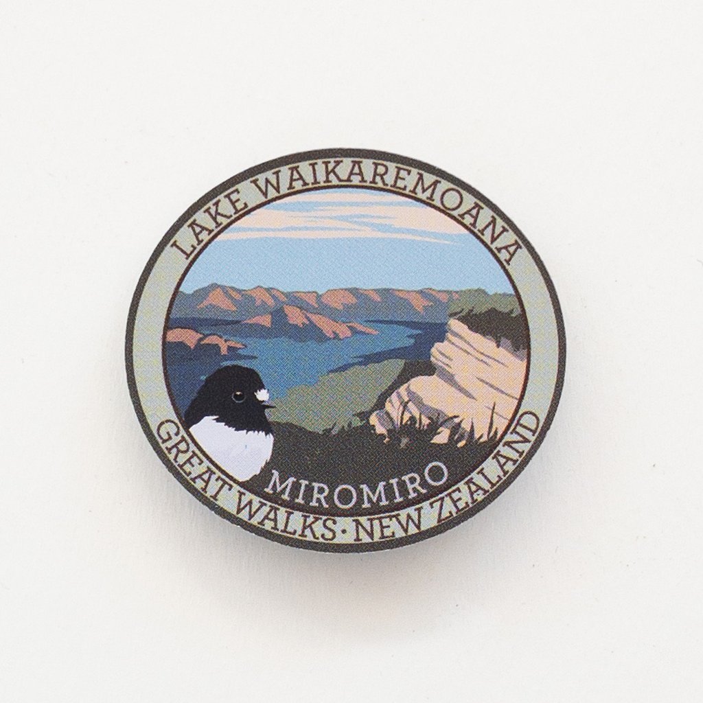 Oval Lake Waikaremoana Track pin, with a miromiro/tomtit bird, blue sky, hills and blue lake.
