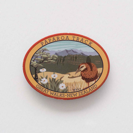 Oval Milford Track pin, with a whio/blue duck, blue peak and mountain buttercup.