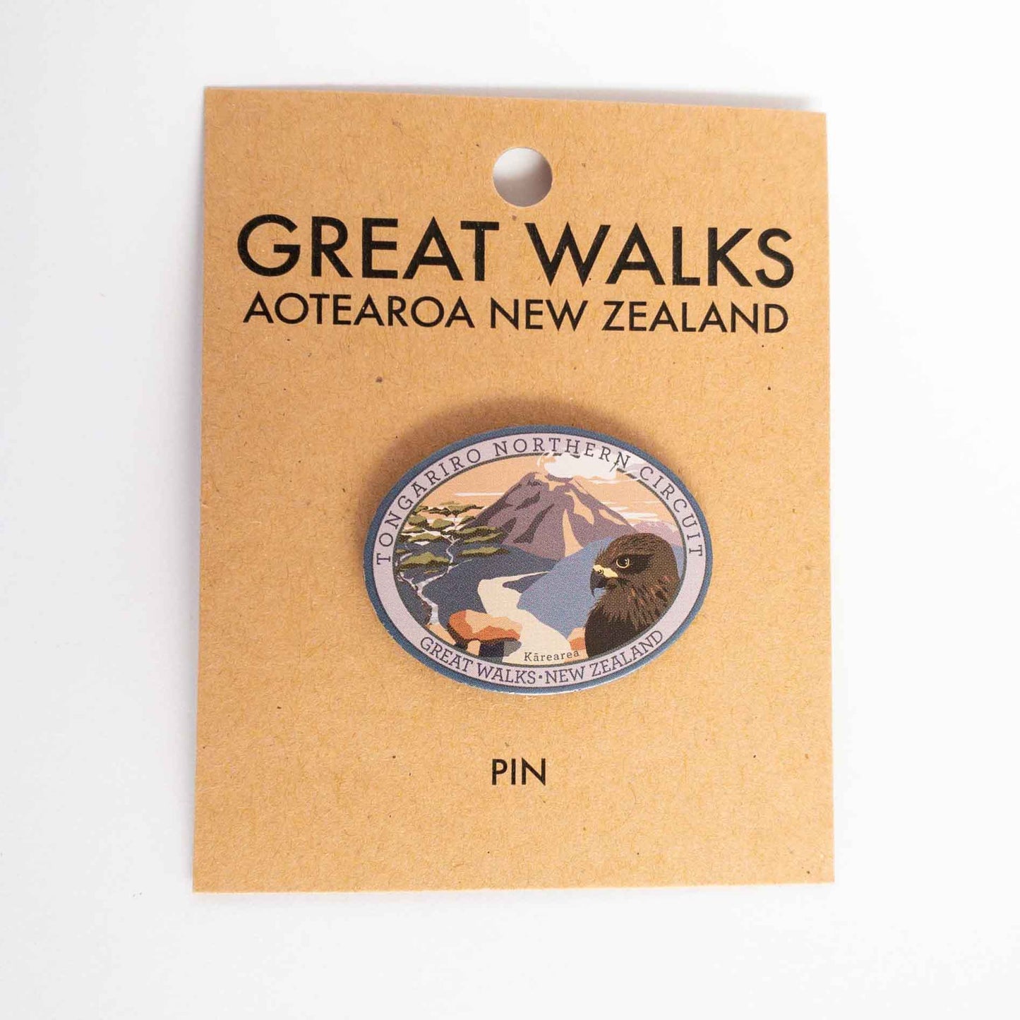 Oval Paparoa Track pin, with a weka, green hills, mountain daisy and tussock, on brown kraft backing card.
