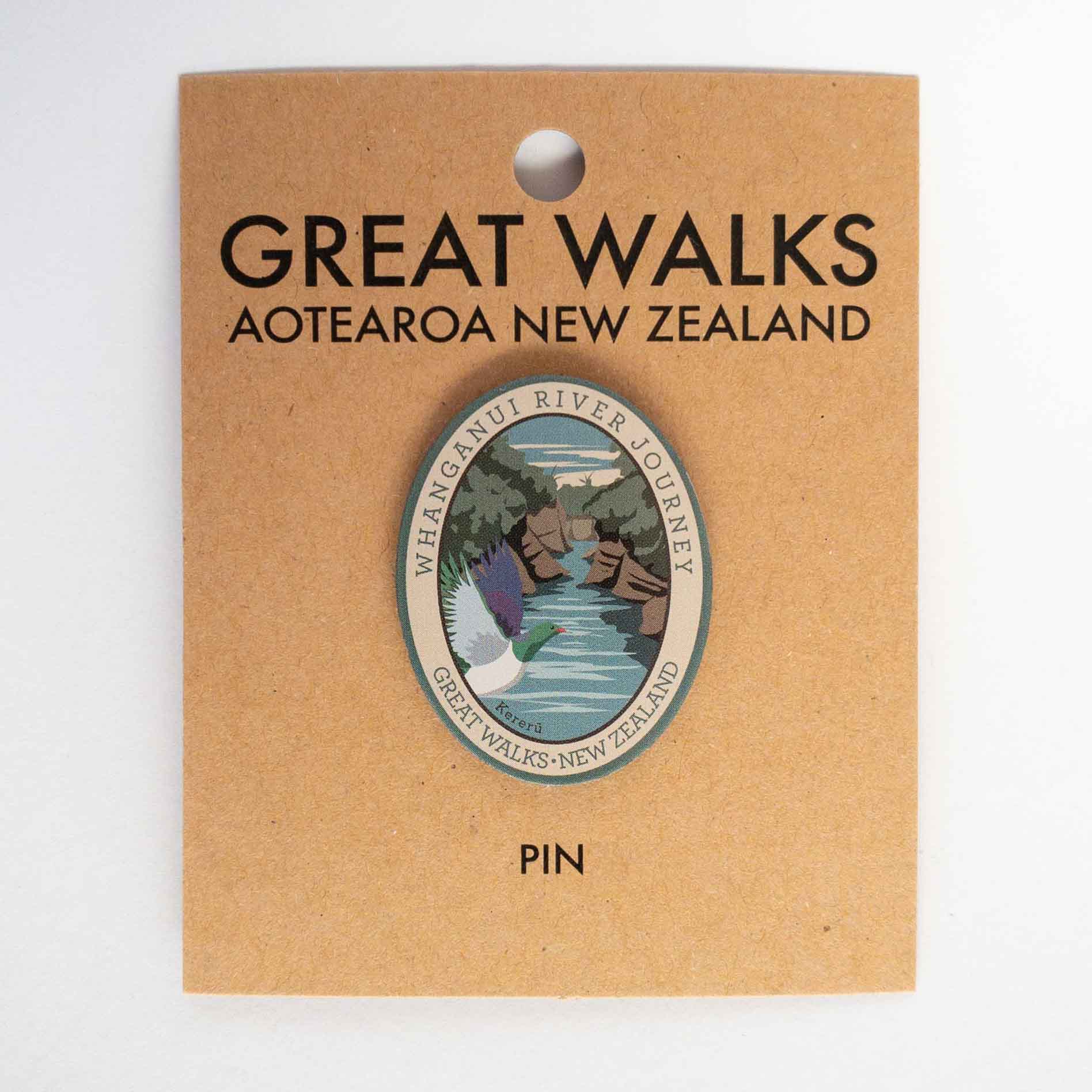 Oval Rakiura Track pin, with a brown kiwi, orange sky, and a chain link sculpture, on brown kraft backing card.